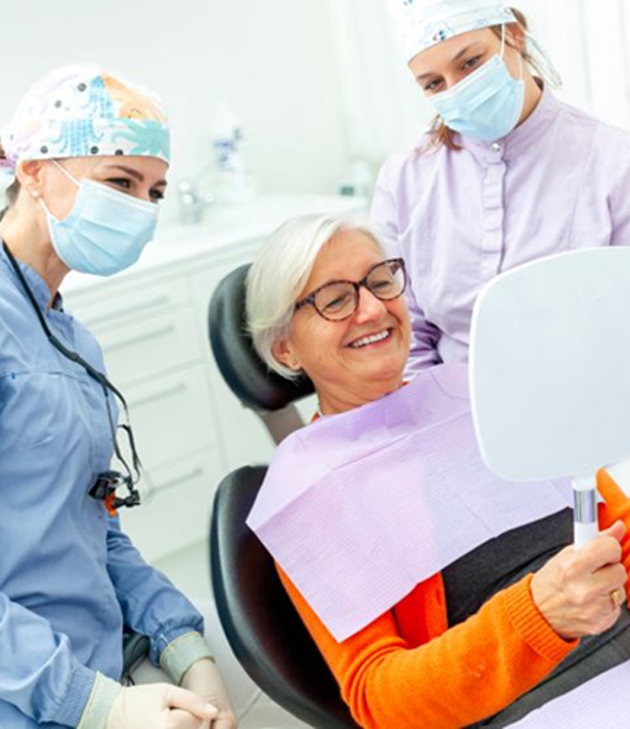 Senior dental patient admiring her smile in the mirror
