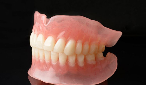 Full upper and lower dentures against dark background