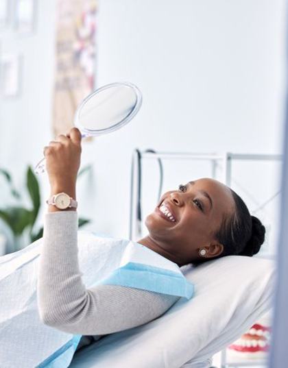 Dental patient looking at her smile in mirror