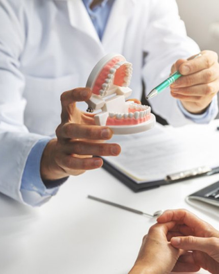 a dentist holding a model of teeth for his patient