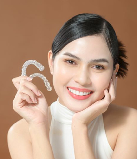 Happy young woman holding two Invisalign aligners