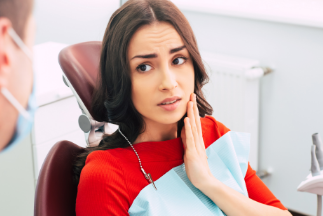 Person wincing in pain and touching the side of their jaw