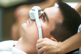 Man relaxing in dental chair with nitrous oxide mask over his nose