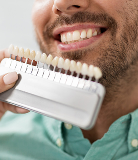 a person holding a shade chart in front of a man’s smile