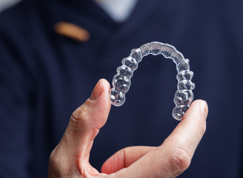 Hand holding clear aligner